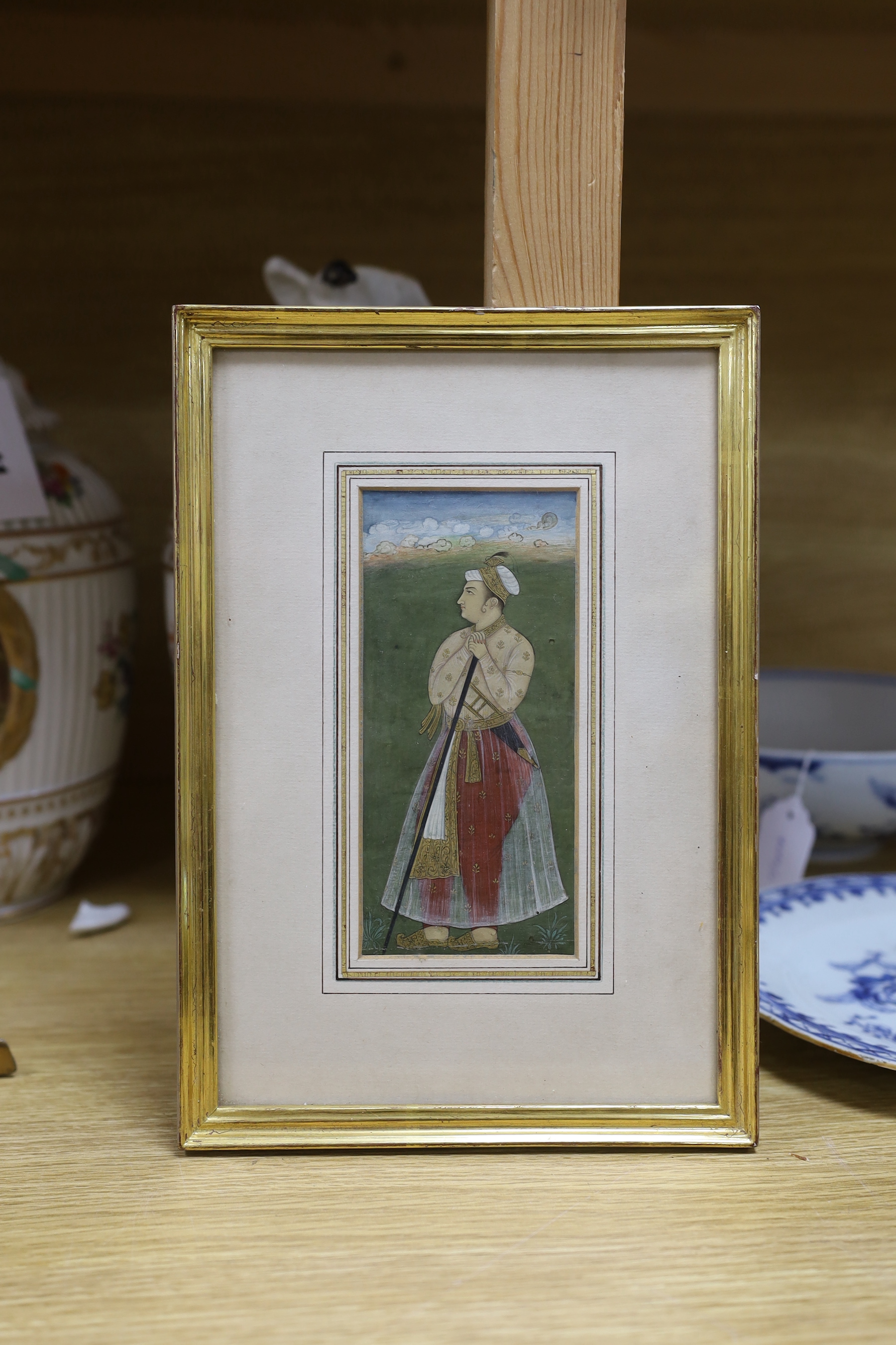Indian School, gouache and watercolour heightened with gilt, Full length portrait of a dignitary standing holding a staff, Mughal style, 15.5 x 7cm